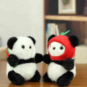 Cute panda plush keychain with red apple hat on dark wood surface with bokeh background