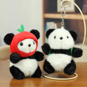 Detailed view of plush panda keychains with red apple hat on a wooden table