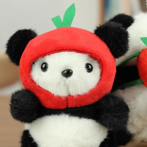 Close-up of cute panda plush keychain wearing a red fruit hat on wooden desk