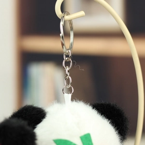 Close-up of fluffy panda plush keychain with green leaf accent and silver metal ring