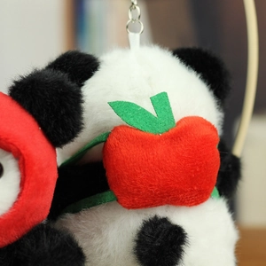 Close-up of soft plush panda keychain featuring a cute red apple ornament on the head