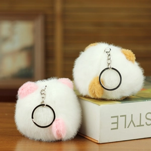 Close-up of white plush red panda keychain with silver metal clip on wooden desk