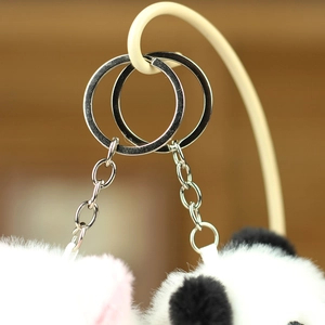Close-up of fluffy pink and panda plush charms with polished silver metal keyrings