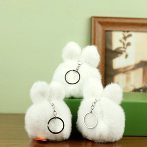 Detalle de tres llaveros de peluche de conejo blanco suave con anillos de metal plateado