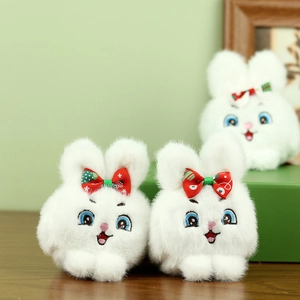 Tres lindos colgantes de conejito de peluche blanco con lazos festivos en mesa madera