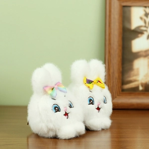 Detalle de dos llaveros de conejito de peluche blanco con lazos de colores sobre madera