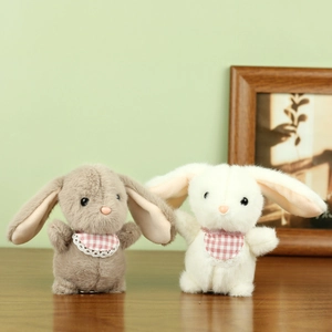 Close-up of white and grey plush rabbits with red checkered bibs on a wooden table