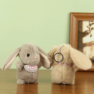 Close-up of cute plush bunny keychains in grey and beige with pink lace bibs