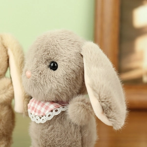 Close-up of soft plush rabbit with pink checkered lace bib on light green background
