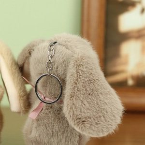 Close-up of soft grey plush rabbit keychain with a pink bow and silver metal clasp