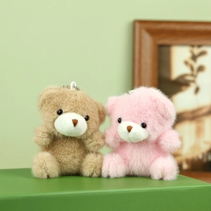 Detailopname van pluche teddybeerhangers in lichtbruin en roze met metalen kralenkettingen