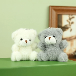 Detailopname van pluizige witte en grijze teddybeer hangers met metalen kettingen