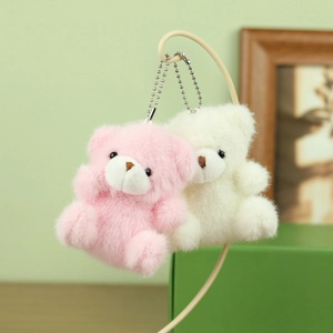 Detail van pluche teddybeertjes in roze en crème met zachte textuur en metalen kettingen