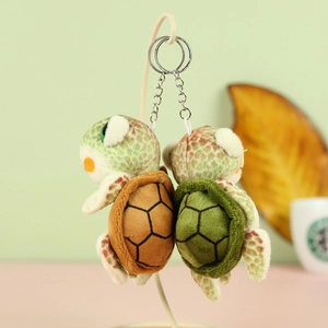 Detail view of two cute plush turtle keychains with green and brown shells and silver rings