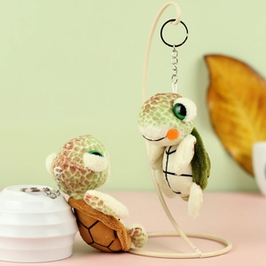 Close-up of cute plush turtle keychains in green and brown with large sparkling eyes