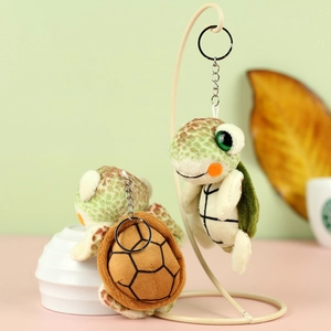 Detailed view of plush turtle keychain with green spots and metal chain on white rack