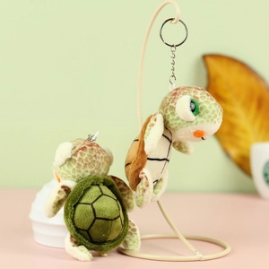 Close-up of cute plush turtle keychains in green and brown with metal rings