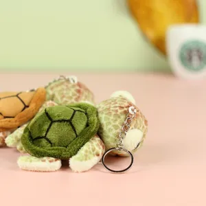 Close-up of cute plush turtle keychain with green and yellow shells and metal ring
