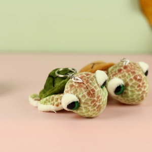 Detail of plush turtle keychains in dark green and light brown with large cute eyes