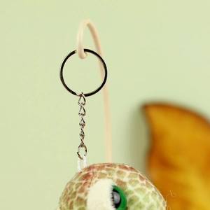 Macro detail of turtle plush keychain with silver ring and soft green textured fabric