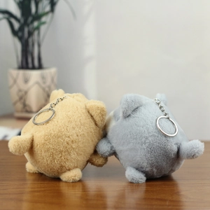 Close-up of brown and grey plush dog charms with metallic silver keychains on wood