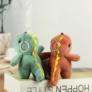Détail de porte-clés dinosaures en peluche vert et orange avec anneaux métalliques