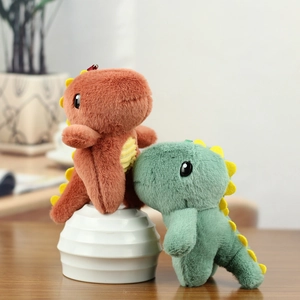 Gros plan de porte-clés dinosaures en peluche vert et rouge sur un bureau en bois