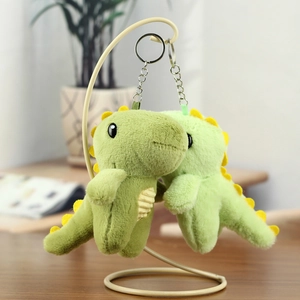 Détail de porte-clés dinosaures en peluche verte avec crêtes jaunes et attaches métalliques