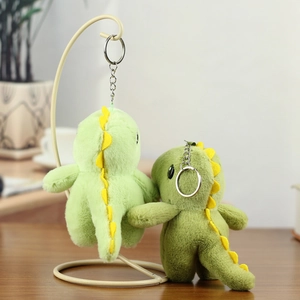 Détail de porte-clés dinosaures en peluche verte avec texture douce sur bureau en bois
