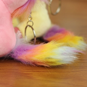 Macro shot of fluffy rainbow plush fur tail and silver metal keychain ring detail
