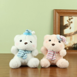Cute plush bear charms in white and pink with striped hats and scarves on wood