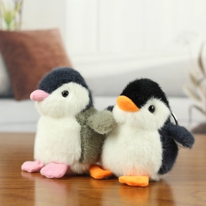 Cute plush penguin keychains in black and pink on a warm wooden surface