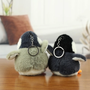 Close-up of cute plush penguin pendants in navy and grey with silver metal keychains