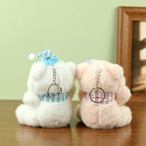Close-up of white and pink plush bear keychains with striped hats and soft fur texture