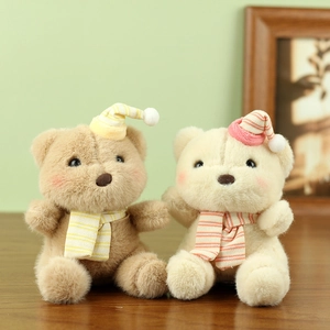 Detail of plush teddy bears with striped hats and scarves in soft pastel colors