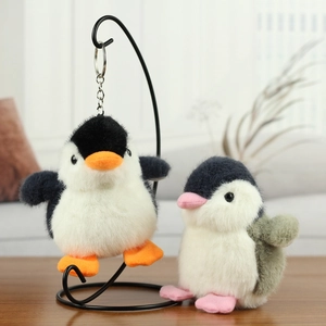 Close-up of soft penguin plush keychains in black and blue with fluffy faux fur texture