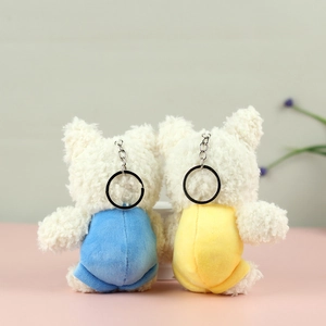 Detail view of plush puppy keychains in blue and yellow outfits with metal hooks