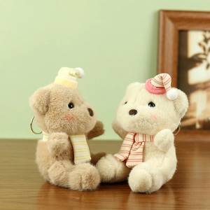 Close-up of cute plush bears in striped hats and scarves with metal keychains