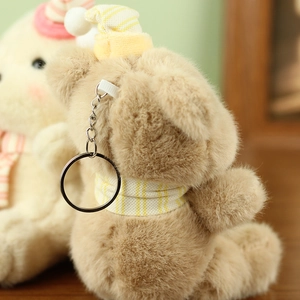 Detail of plush bear keychain with yellow striped knit hat and scarf texture