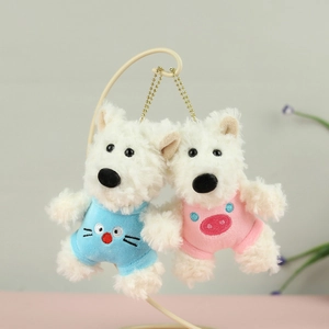 Detail of white plush Westie puppy keychains wearing blue and pink embroidered outfits