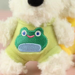 Macro detail of plush dog toy wearing green vest with vivid frog embroidery and soft fur
