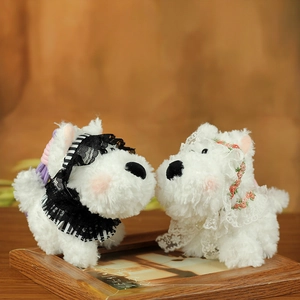 Close-up of Westie plush keychains with delicate lace collars on a wooden frame