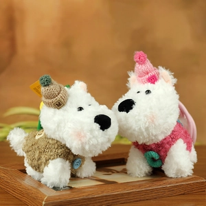 Close-up of white Westie plush keychains wearing cozy knitted brown and pink outfits
