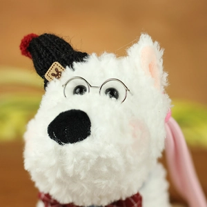 Close-up of Westie plush keychain featuring a knitted hat, glasses, and red plaid bow tie