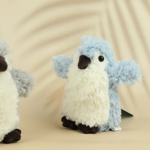 Detail of cute blue plush penguin keychain with soft texture and gentle plant shadows