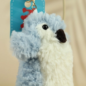 Close-up of soft light blue plush penguin pendant with golden metal clasp and heart tag