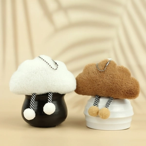 Cute white and brown plush cloud keychain charms with striped legs on minimalist pedestals