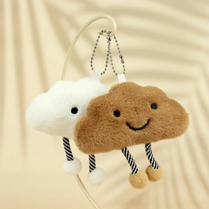 Close-up of cute white and brown plush cloud charms with striped legs and metal chains