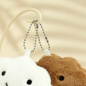 Detailed close-up of white and brown plush bunny pendants with silver bead chains