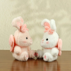 Detail von rosa und weißen Plüsch-Hasen-Anhängern mit Schleifen und Flügel-Akzenten